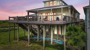 A two-story house with a balcony, a staircase, and a view of the surrounding landscape. - A Stairway To Heaven 4 Bedroom Home (Port Bolivar)