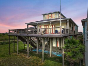 A two-story house with a balcony, a staircase, and a view of the surrounding landscape. - A Stairway To Heaven 4 Bedroom Home (Port Bolivar)