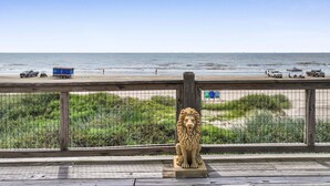 A lion statue on a wooden platform overlooking a beach with vehicles and people. - A Stairway To Heaven 4 Bedroom Home (Port Bolivar)
