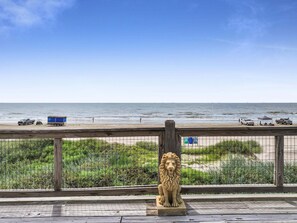 A lion statue on a wooden platform overlooking a beach with vehicles and people. - A Stairway To Heaven 4 Bedroom Home (Port Bolivar)
