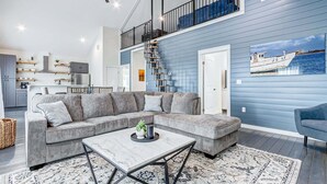 Ein modernes Wohnzimmer mit Ecksofa, Couchtisch und einer Treppe zu einer oberen Ebene.