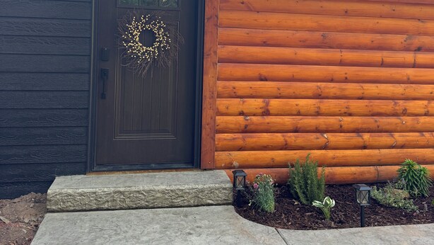 A log cabin with a dark wooden door, a wreath, and a small porch area. - Fabulous 3-bedroom cabin in welcoming Webb Lake perfect for relaxing (WEBB LAKE)