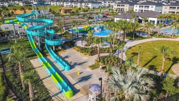 Un parc aquatique doté de nombreux toboggans et d’un espace piscine entouré de palmiers, avec un complexe résidentiel en arrière-plan.