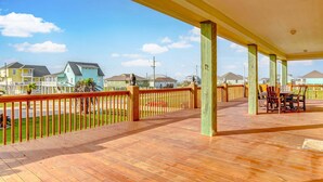 Une terrasse extérieure couverte, dotée d’un plancher en bois, d’une rambarde et d’une table avec des chaises.
