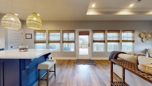 Una cocina moderna con una isla central, ventanas amplias y un rincón de estar acogedor.