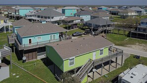 Zona residencial costera con varias casas de dos pisos, algunas con terrazas y unas pocas con pasarelas elevadas.
