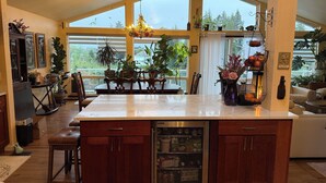 A spacious kitchen with a large island, wooden cabinets, a built-in refrigerator, and a view through large windows. - The Green Heaven at the Lake (Lake Tapps)