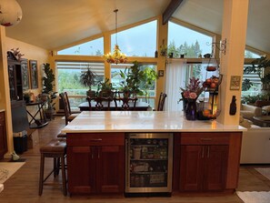 Eine großzügige Küche mit einer großen Kochinsel, Holzschränken, einem integrierten Kühlschrank und Blick durch große Fenster.