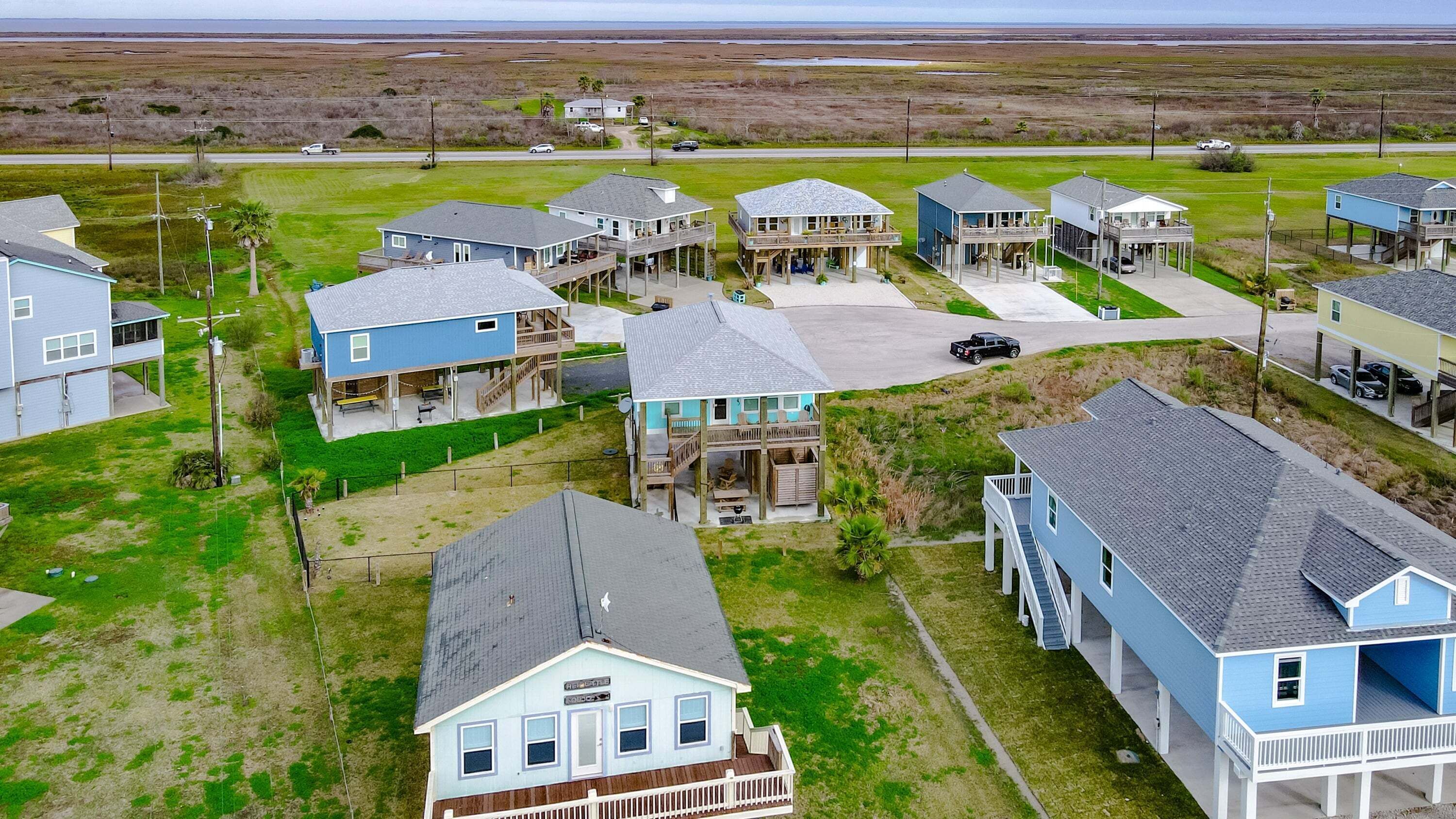 Zona residencial a la costa amb diverses cases de dos pisos, balcons, un espai central obert i vistes a l'oceà.