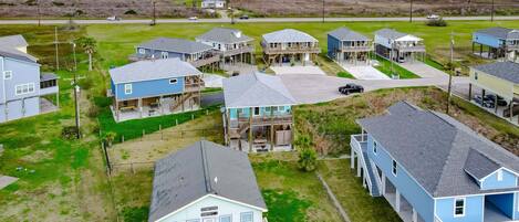 Zona residencial a la costa amb diverses cases de dos pisos, balcons, un espai central obert i vistes a l'oceà.