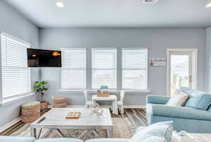 A living room with a TV, white furniture, a plant, and a window with blinds. - Afterdunedelight 3 Bedroom Home (Port Bolivar)