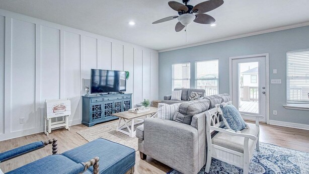 Ein Wohnzimmer mit Fernseher, blauem Schrank, grauem Sofa und Deckenventilator.