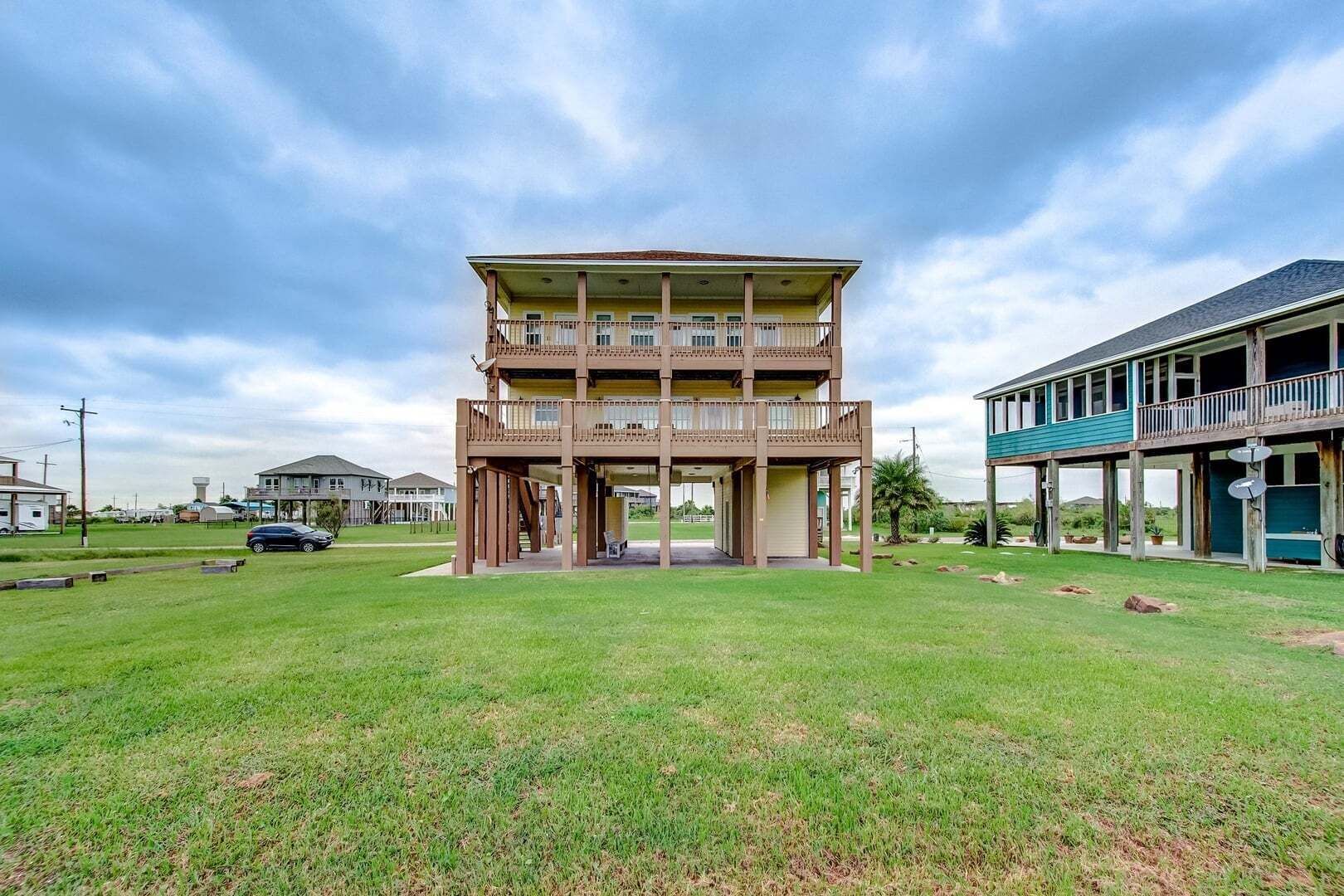 A two-story building with a balcony on the upper floor, surrounded by a grassy area.