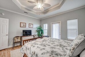 A bedroom with a bed, a desk with a TV, a ceiling fan, and a window. - Oceanview 4 Bedroom Home (Port Bolivar)