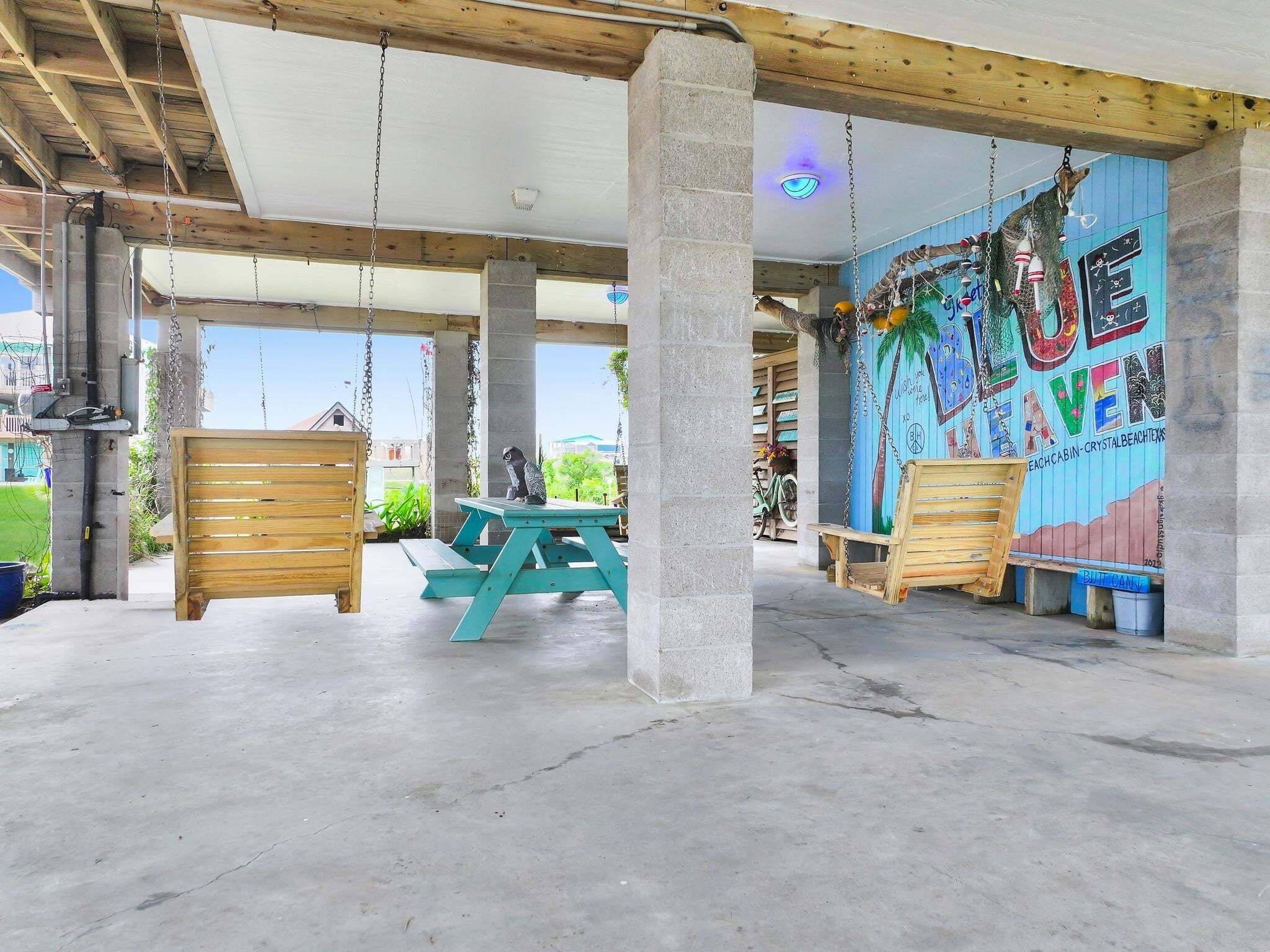 An outdoor covered patio area with a mural, wooden benches, and a picnic table.