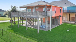 Ein zweistöckiges Haus mit Balkon, überdachter Terrasse und kleiner Terrassenfläche.
