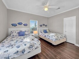 A bedroom with two beds, a ceiling fan, and a window with blinds.