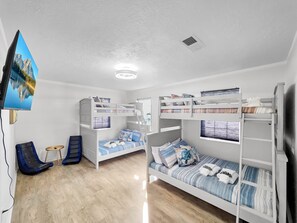 Ein Zimmer mit Etagenbetten, einem Fernseher, einem Schreibtisch und einem Stuhl.