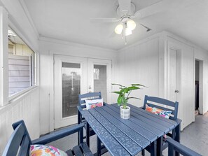 Ein Essbereich mit Tisch, Stühlen, einem Deckenventilator und einem Blumentopf.
