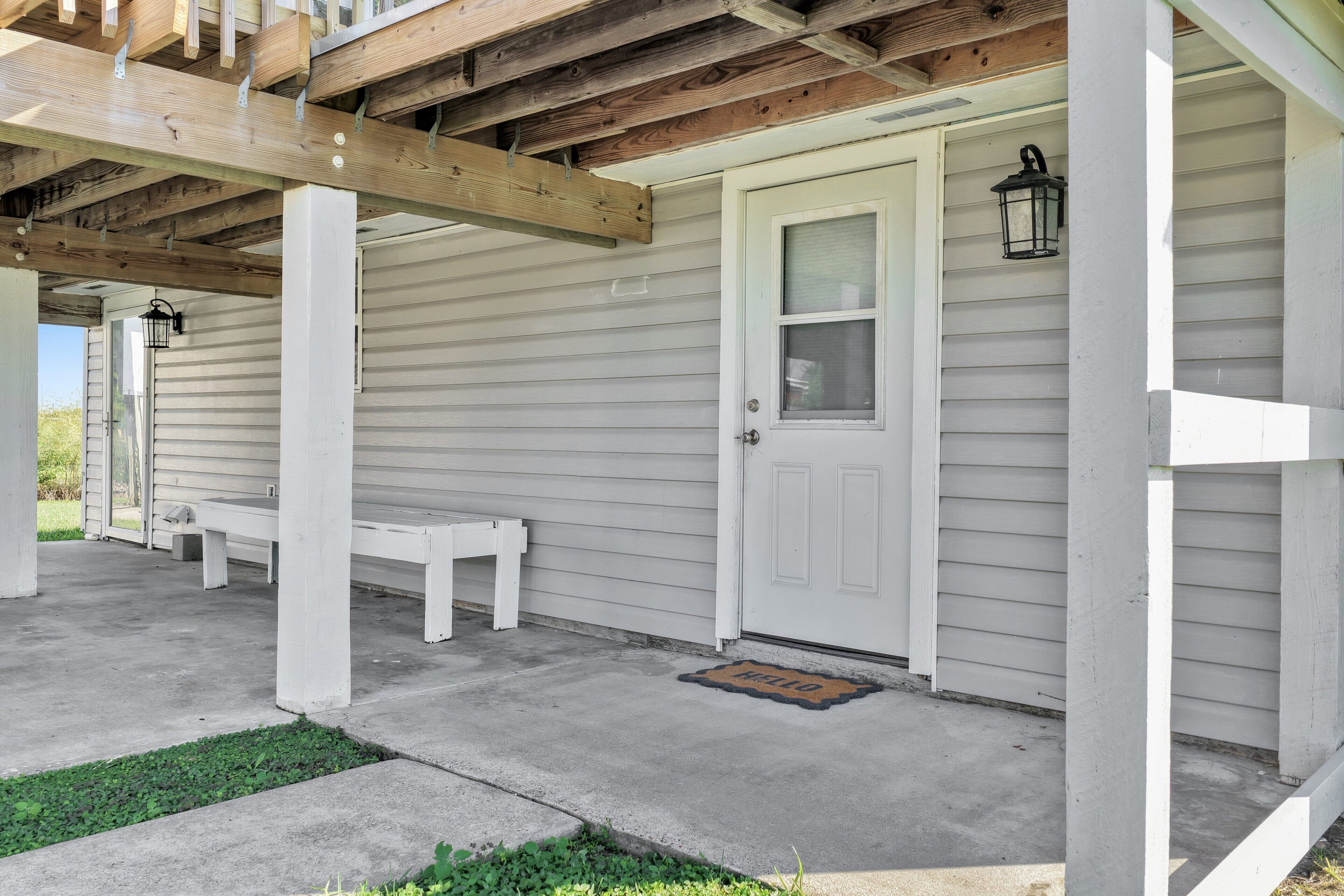 A porch with a white door, a bench, and a doormat.