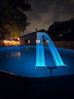 A swimming pool with a water feature at night. - Modern Home with Backyard pool + Mini Golf! (San Antonio)