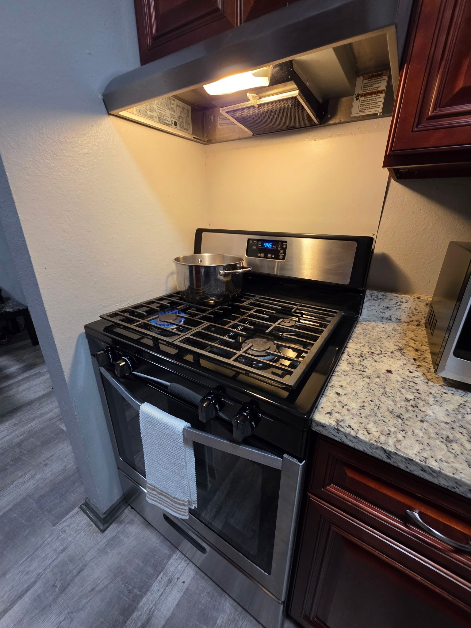 Una cocina con estufa de acero inoxidable, horno y encimera de granito.