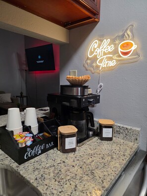 A coffee bar setup with a coffee machine, cups, and jars of coffee beans. - Modern Home with Backyard pool + Mini Golf! (San Antonio)