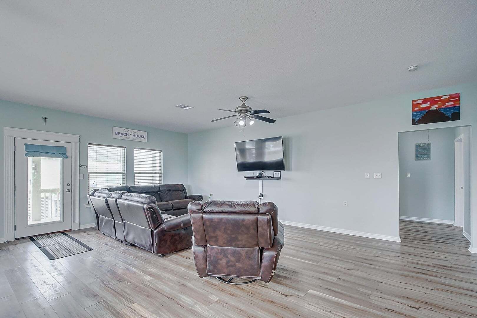 Un salon spacieux doté d’un ventilateur de plafond, d’un téléviseur à écran plat et d’un fauteuil inclinable en cuir.