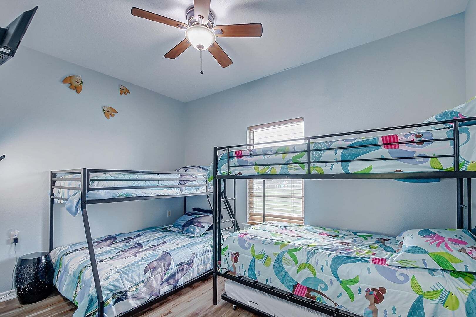 A bunk bed room with a ceiling fan, a window with blinds, and a wall with fish decorations.