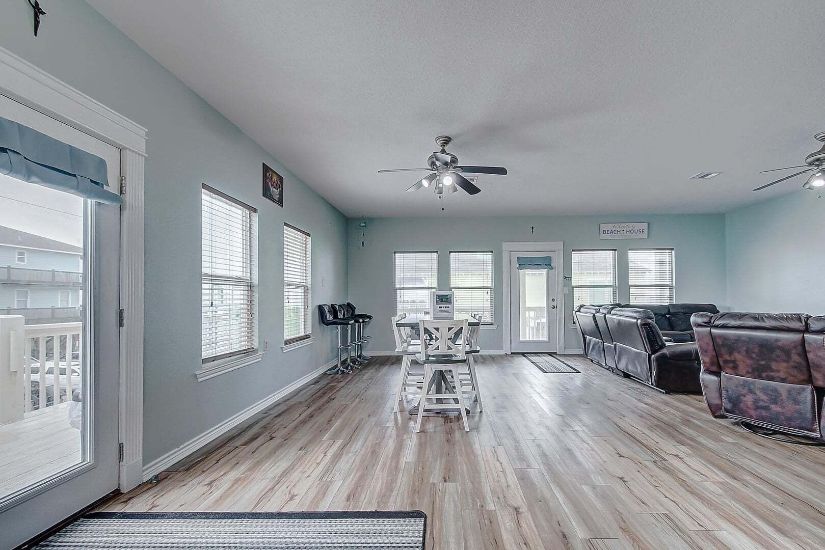 Un salon spacieux comprenant un coin repas, un ventilateur de plafond et une pancarte indiquant « Maison de plage ».