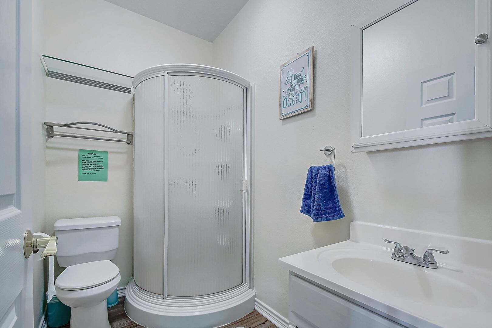 A bathroom with a toilet, a shower enclosure, a sink, and a mirror.