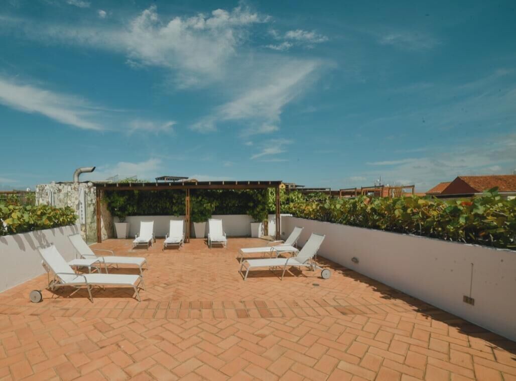 Una terraza en la azotea con sillones de descanso, una pérgola y vistas al cielo.