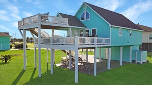 Une maison à deux étages dotée d’un balcon, d’une terrasse couverte et d’une petite plateforme.