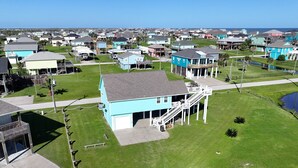 Un quartier résidentiel avec des maisons, un grand bâtiment bleu doté d’un garage et un petit étang.