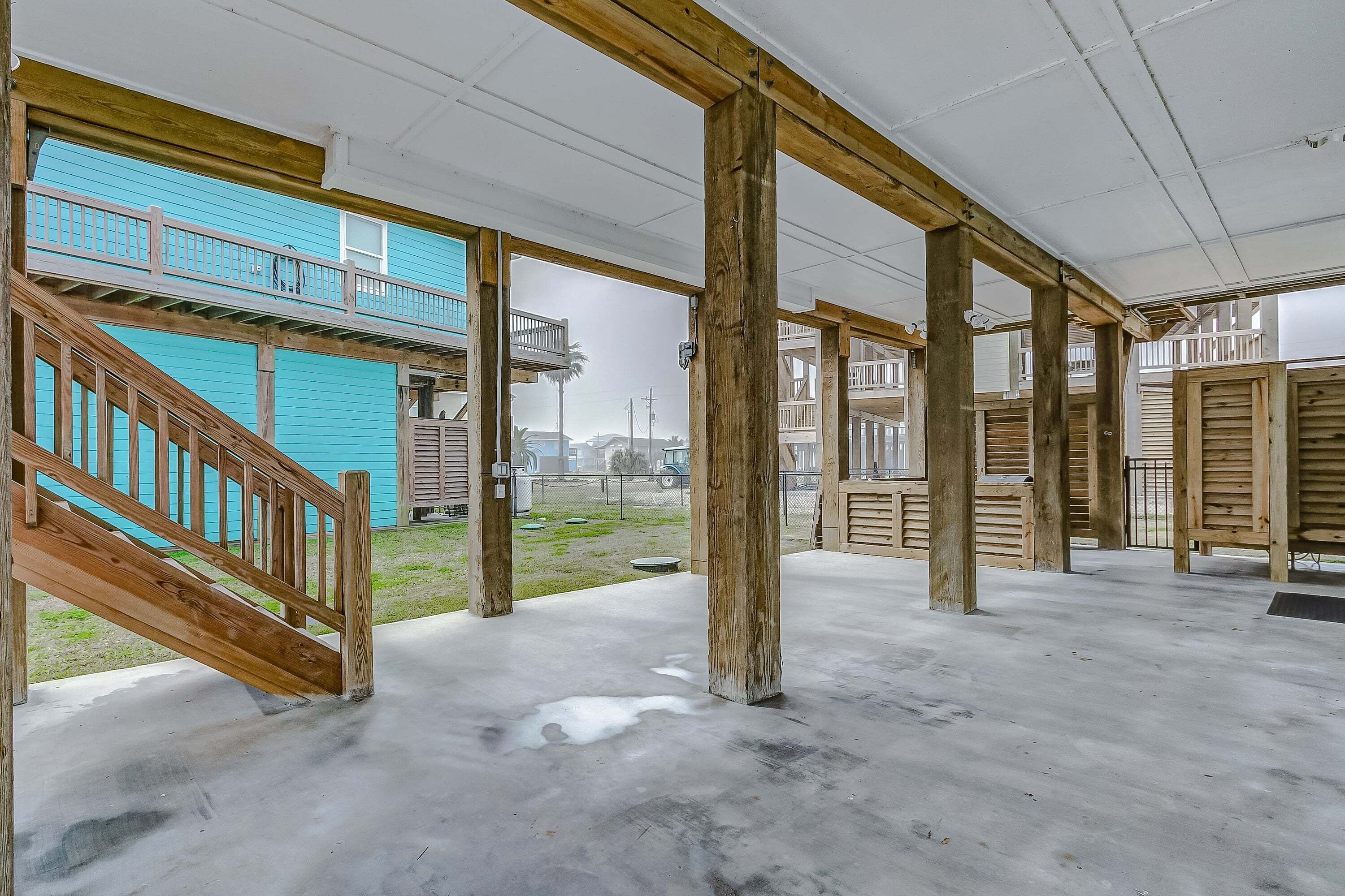 Un bâtiment doté d’un escalier en bois, d’un plancher en béton et offrant une vue sur un immeuble bleu en arrière-plan.