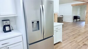 Una cocina moderna con refrigerador de acero inoxidable, cafetera y piso de madera.