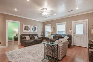 A living room with a ceiling fan, two couches, a coffee table, and a patterned rug. - The Bungaleaux 3 Bedroom Home (Port Bolivar)