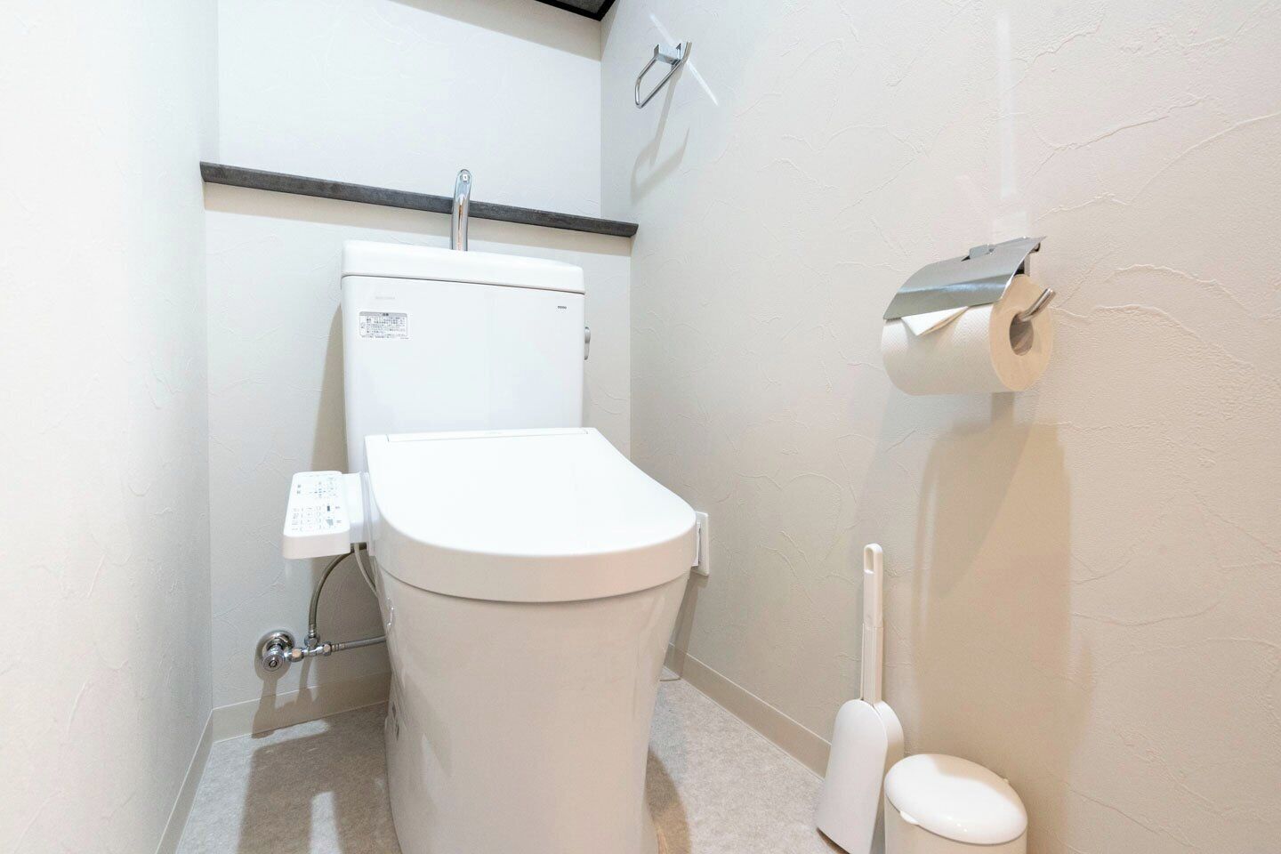 Et lille, hvidt badeværelse med toilet, bidet og toiletpapirholder.