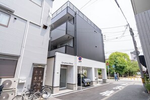 A modern building with a white facade, a black entrance, and a sign reading 'La grace Ahane'. - La grace Akane (Osaka)