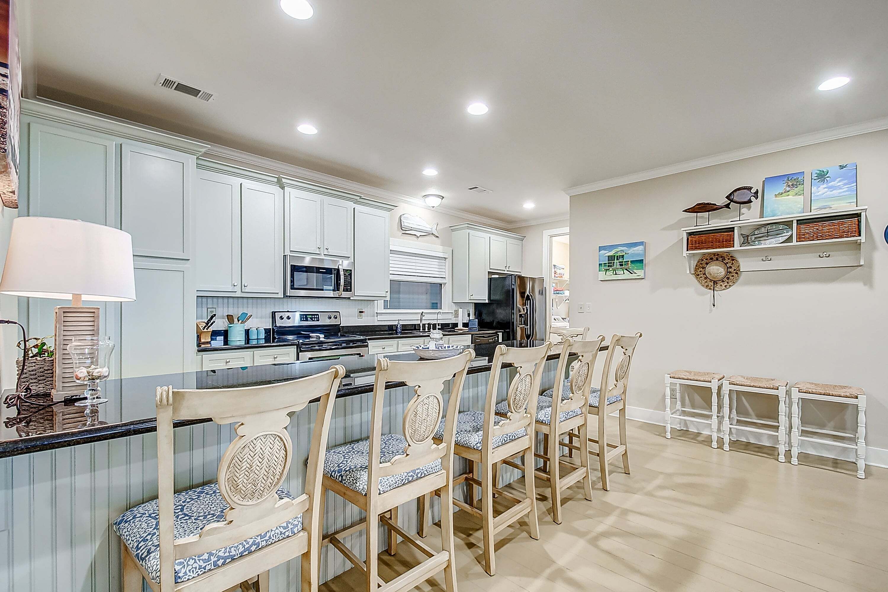 A kitchen with white cabinets, a central island with bar stools, and a microwave.