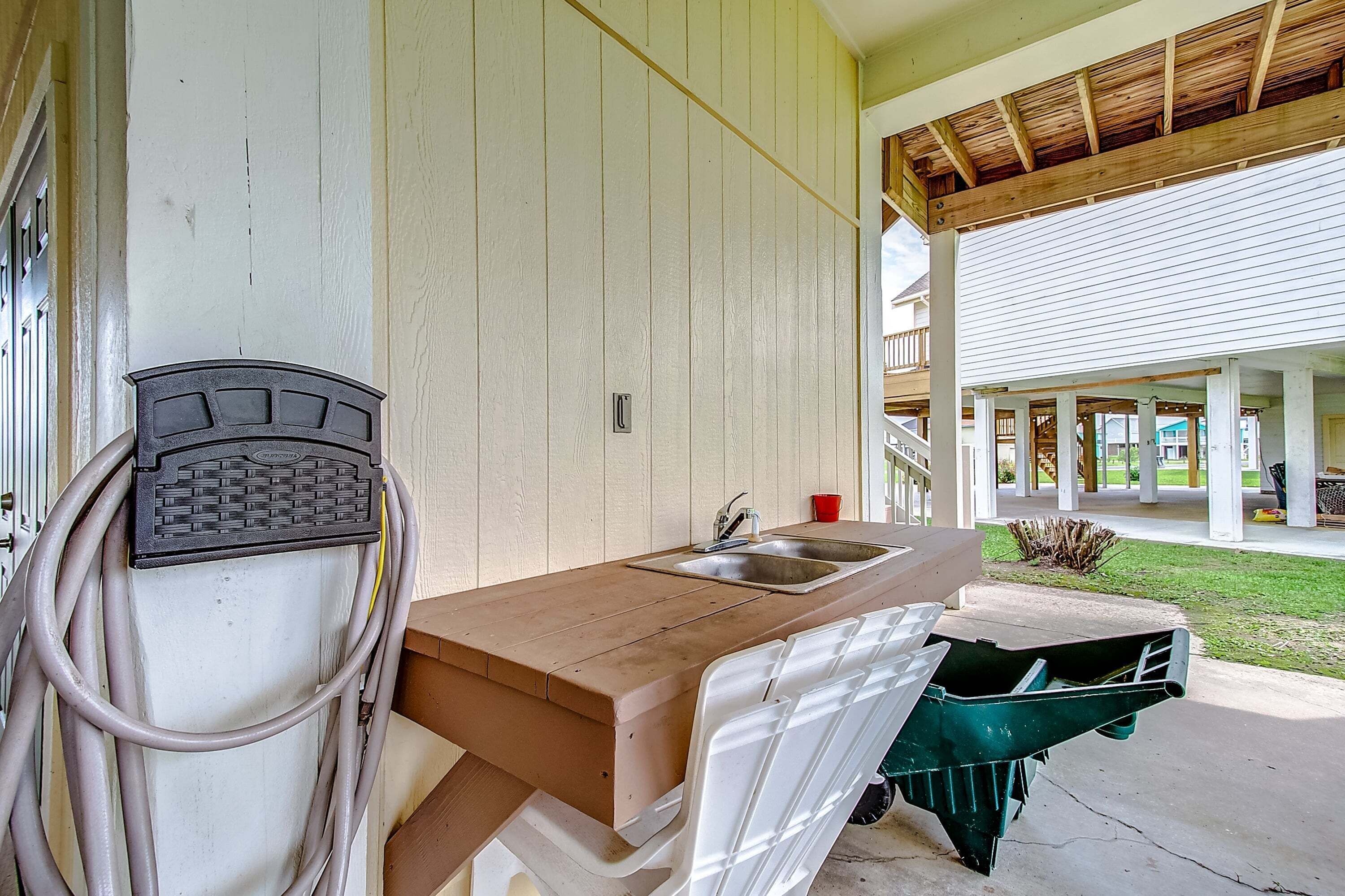 A kitchen with a sink, a hose, and a green trash bin.
