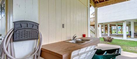 A kitchen with a sink, a hose, and a green trash bin.
