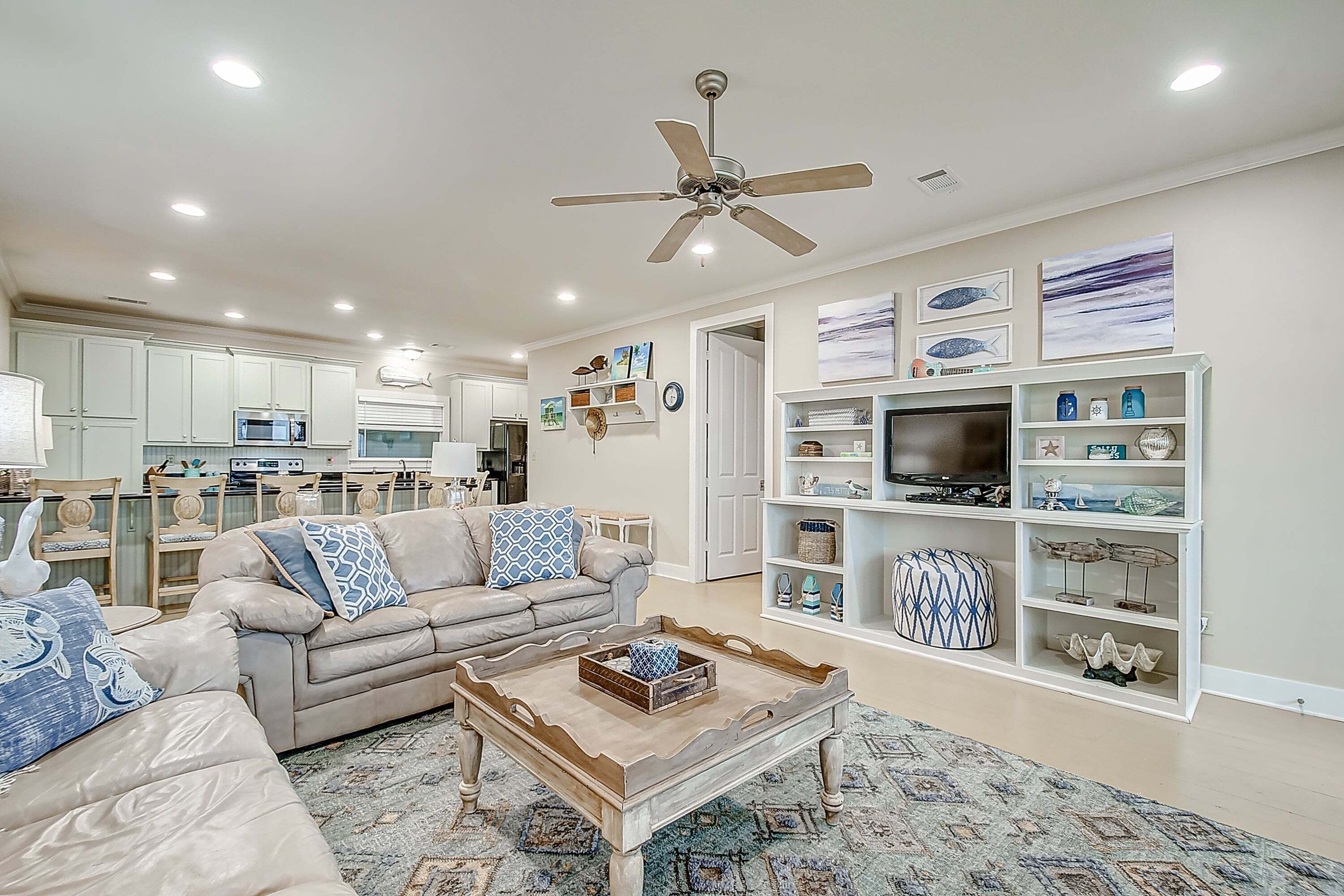 A living room with a sofa, coffee table, TV stand, and ceiling fan.