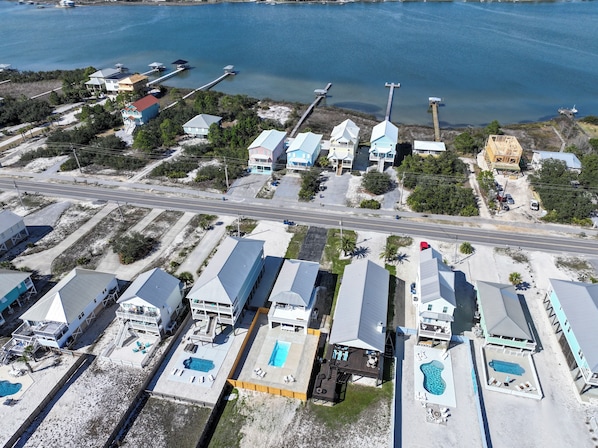 An aerial view of a coastal property with multiple buildings, a road, and a marina. - Sand in my boots - 2 Bedroom home in GULF SHORES with private pool and bikes (Gulf Shores)