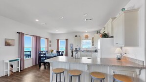 A modern kitchen with a central island, bar stools, and a view of the ocean. - Sea Mist 2 Bedroom Home (Port Bolivar)