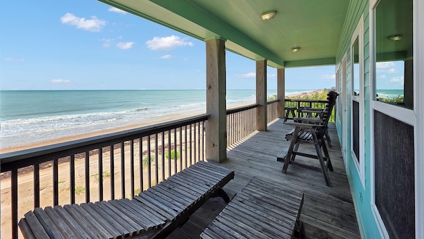 A wooden deck with a view of the ocean, a bench, and a table. - Sea Mist 2 Bedroom Home (Port Bolivar)