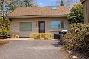 A single-story house with a red door, two windows with shutters, and a small skylight.