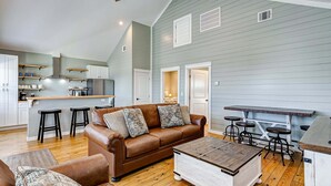 A spacious living area with a brown leather sofa, a wooden coffee table, and a kitchen in the background. - Sea You Soon 2 Bedroom Home (Coffeyville)