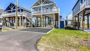 A beachfront property with elevated structures, a paved walkway, and a grassy area. - Sea You Soon 2 Bedroom Home (Coffeyville)