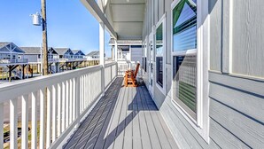 A wooden deck with a railing, a bench, and a covered area with windows. - Sea You Soon 2 Bedroom Home (Coffeyville)